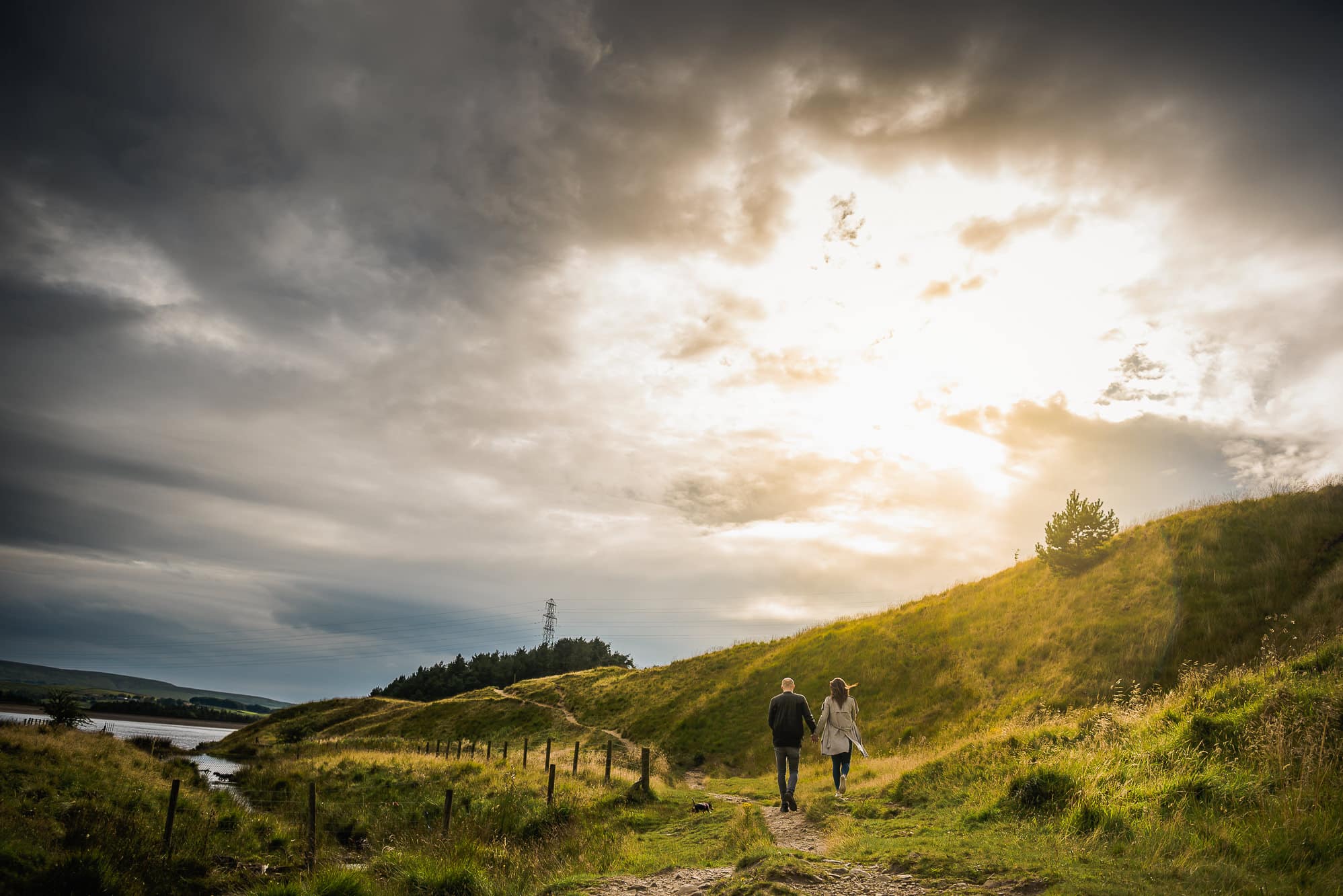 couple walking into sunset at Hurstwood Reservoir