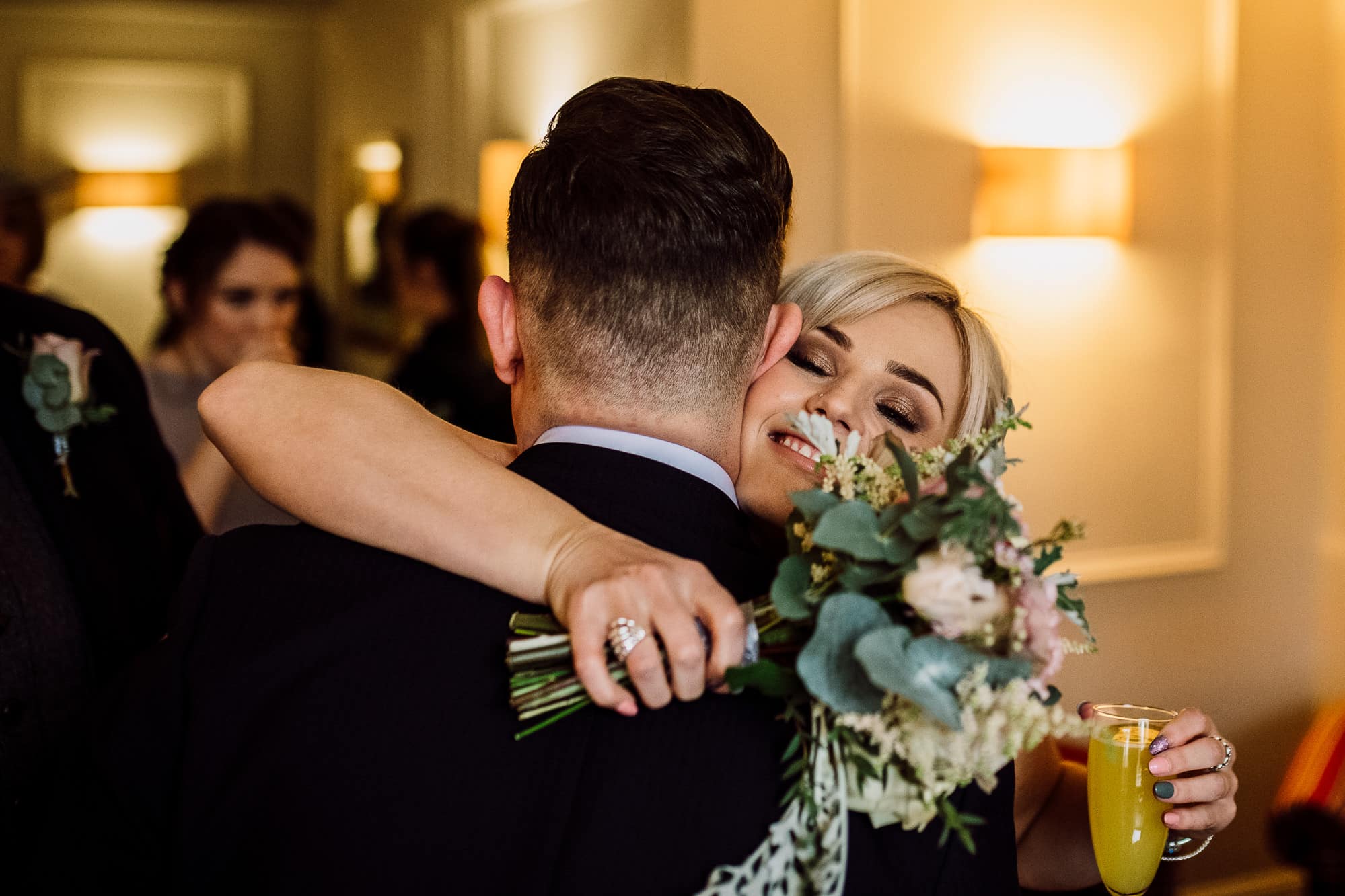 Crabwall Manor Wedding Photography | Mark & Beth 14 The groom is hugged by the bridesmaid during reception drinks
