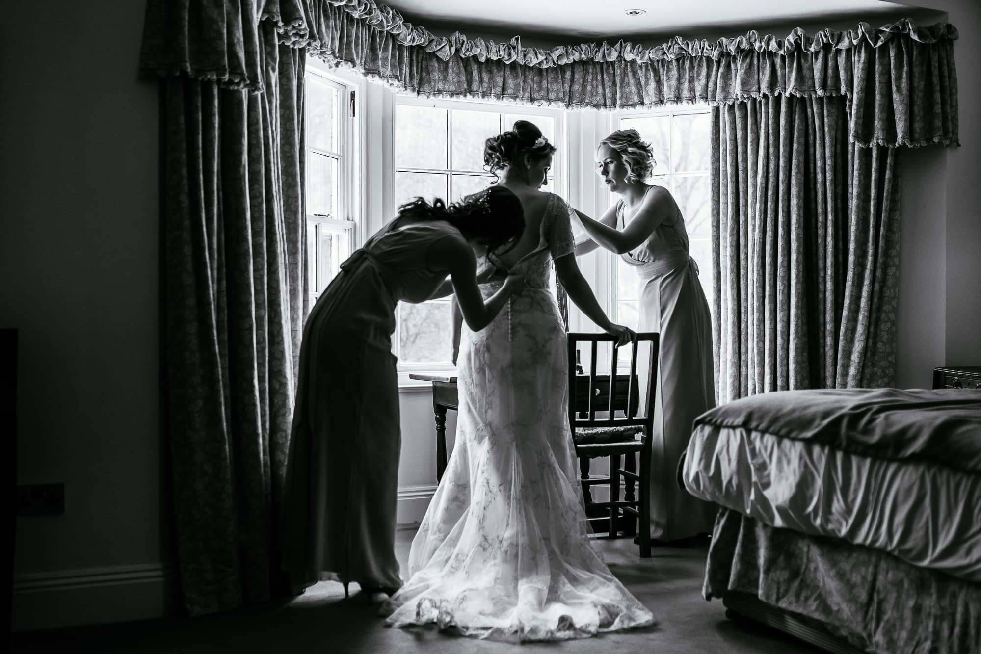 The bride getting into her dress and being helped by her bridesmaids