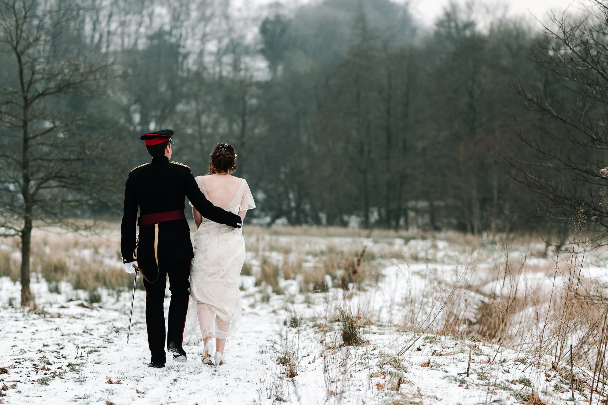 A photo from behind of the bride and groom walking in the snow