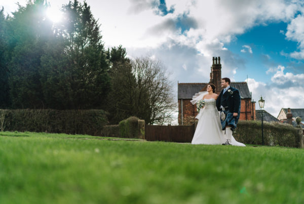 bride and groom walking outside bestow manor with the sun coming through