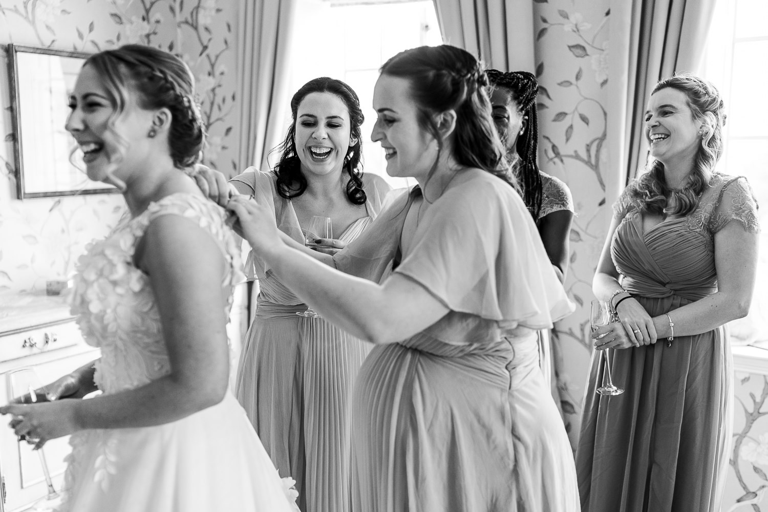 Bride putting her dress on with her bridesmaids