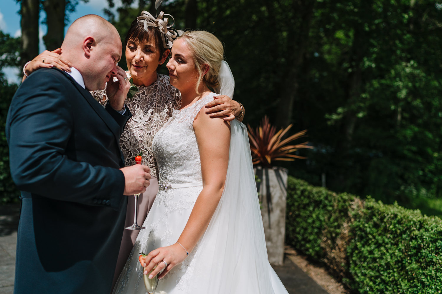 Bride and groom hugging mother of bride at the Mere