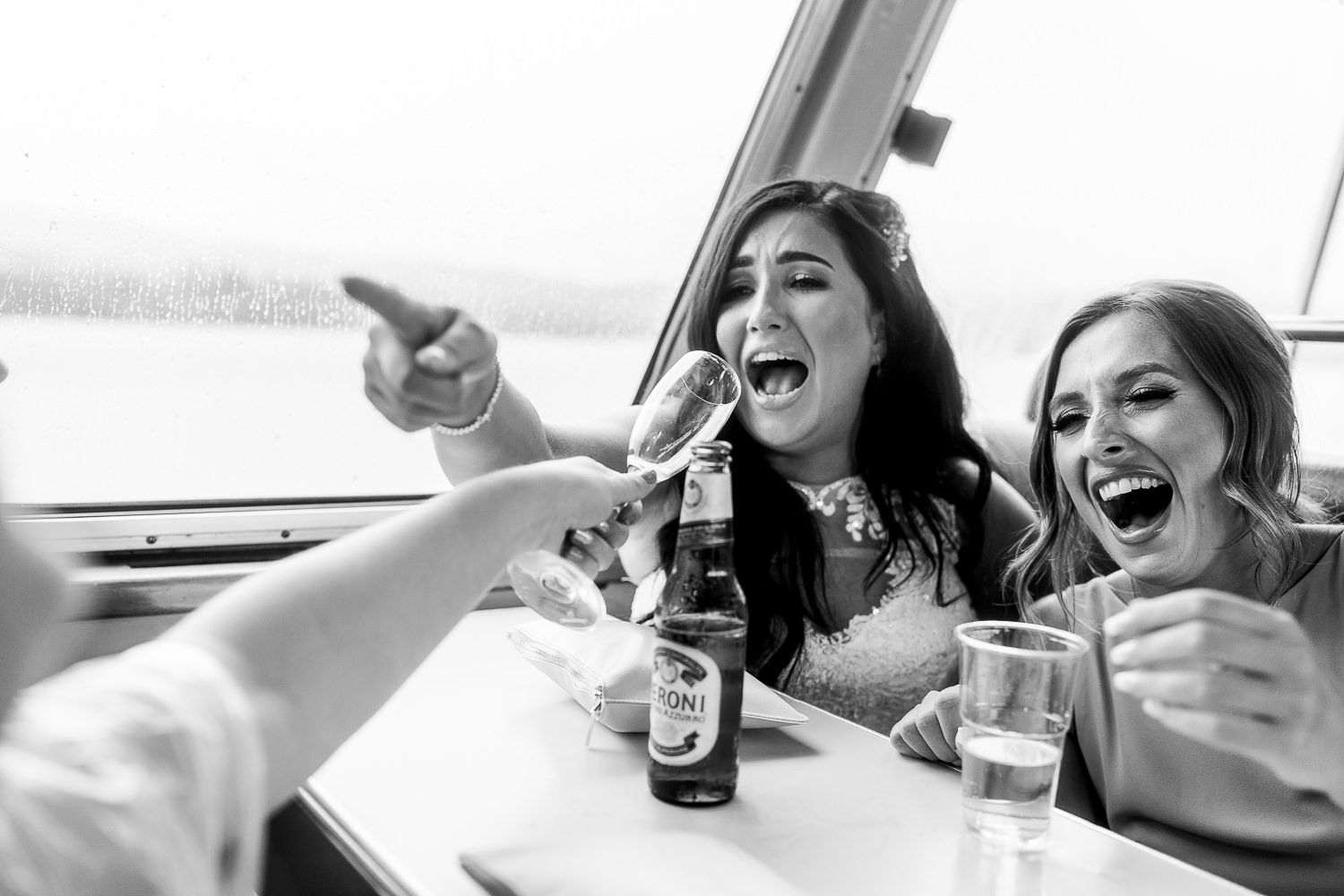 bride laughing on the boat wit bridesmaid on Lake Windermere