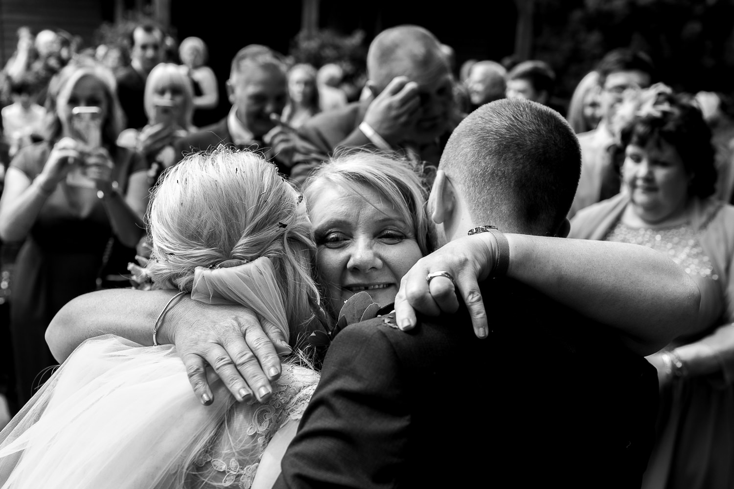 Bride and groom hugging a guest