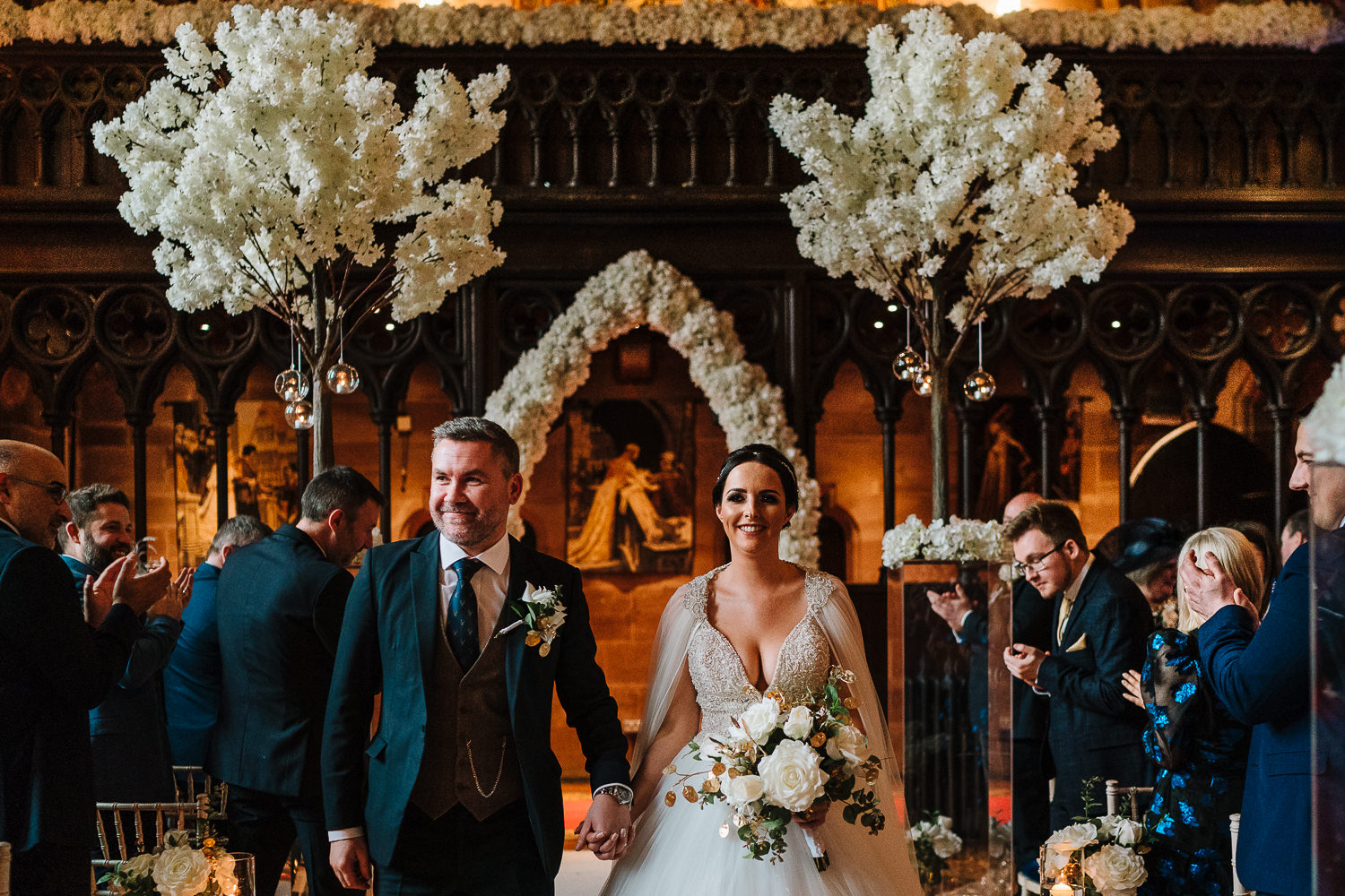 bride and groom walking out of the Great Hall at Peckforton Castle