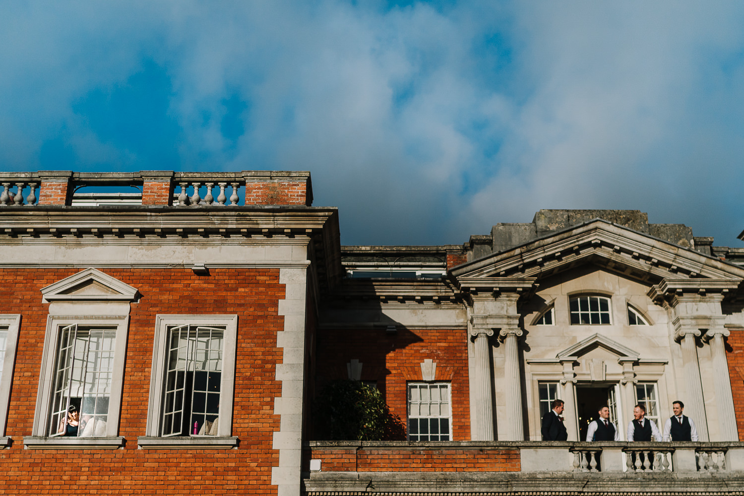 Groomsmen on the balcony and bride in the window