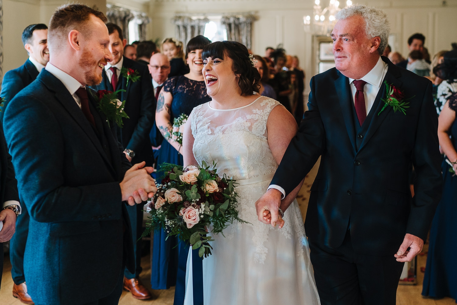 Bride laughing at the bottom of the aisle at Eaves hall