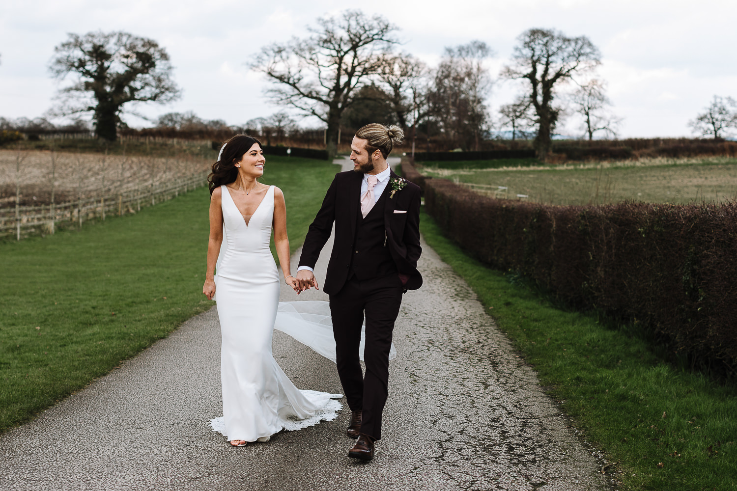 Sandhole Oak Barn Wedding Photography 56 bride and groom walking back to the barn from the drive