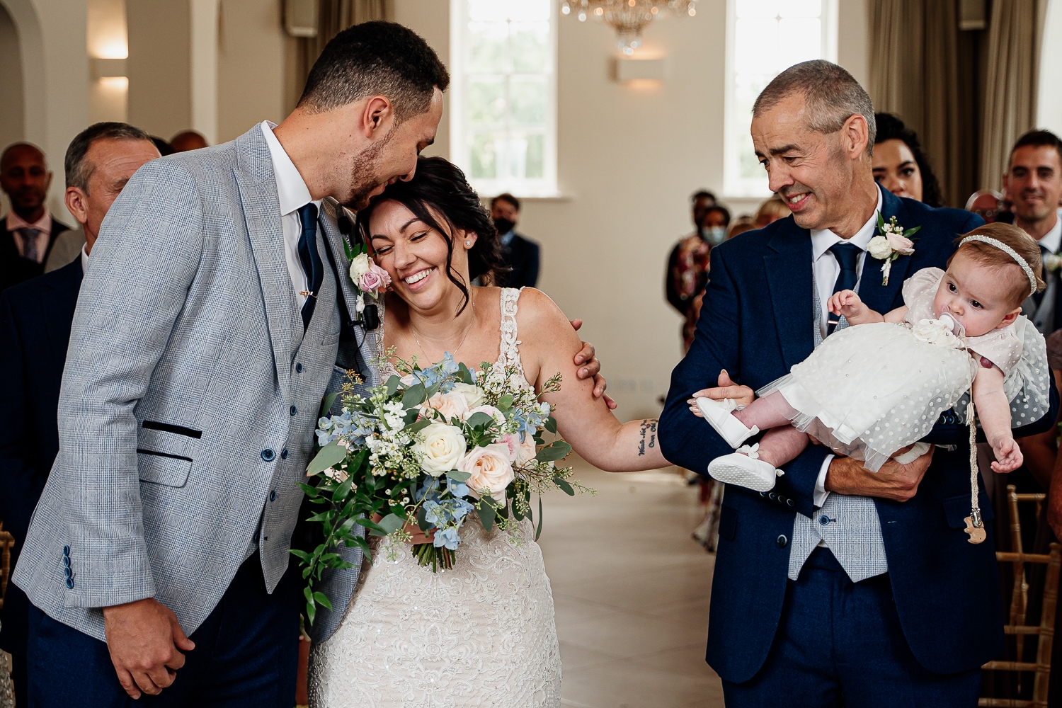 Groom kissing the bride as she arrivals down the aisle