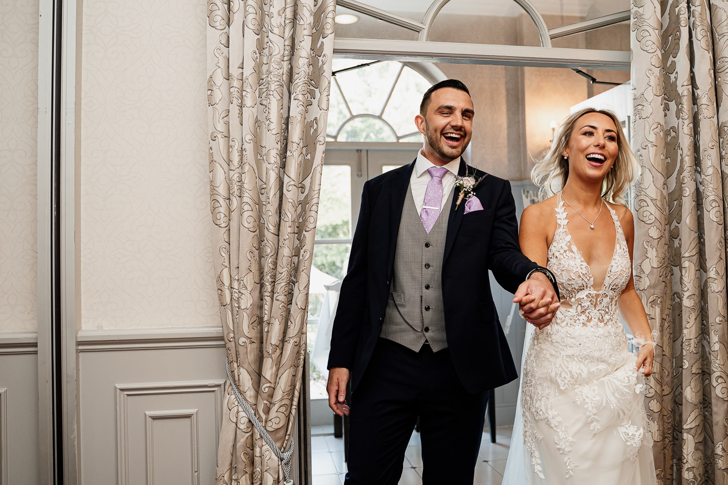 Bride and groom walking into St Andrews suite at Mottram Hall