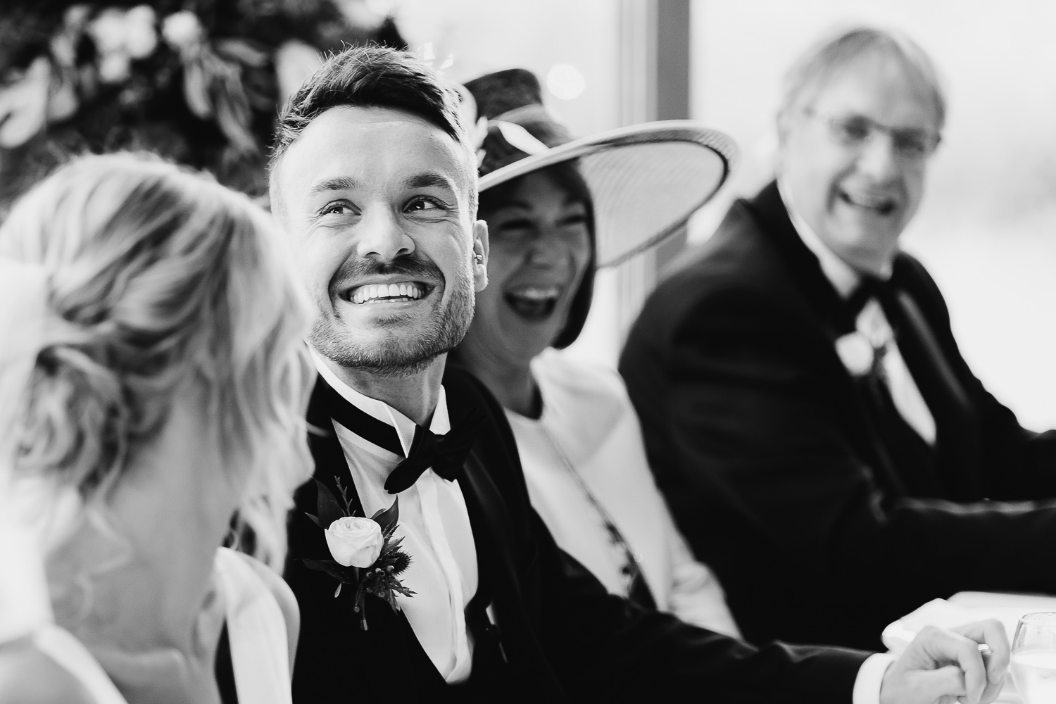 Groom and his parents smiling during father of bride speech