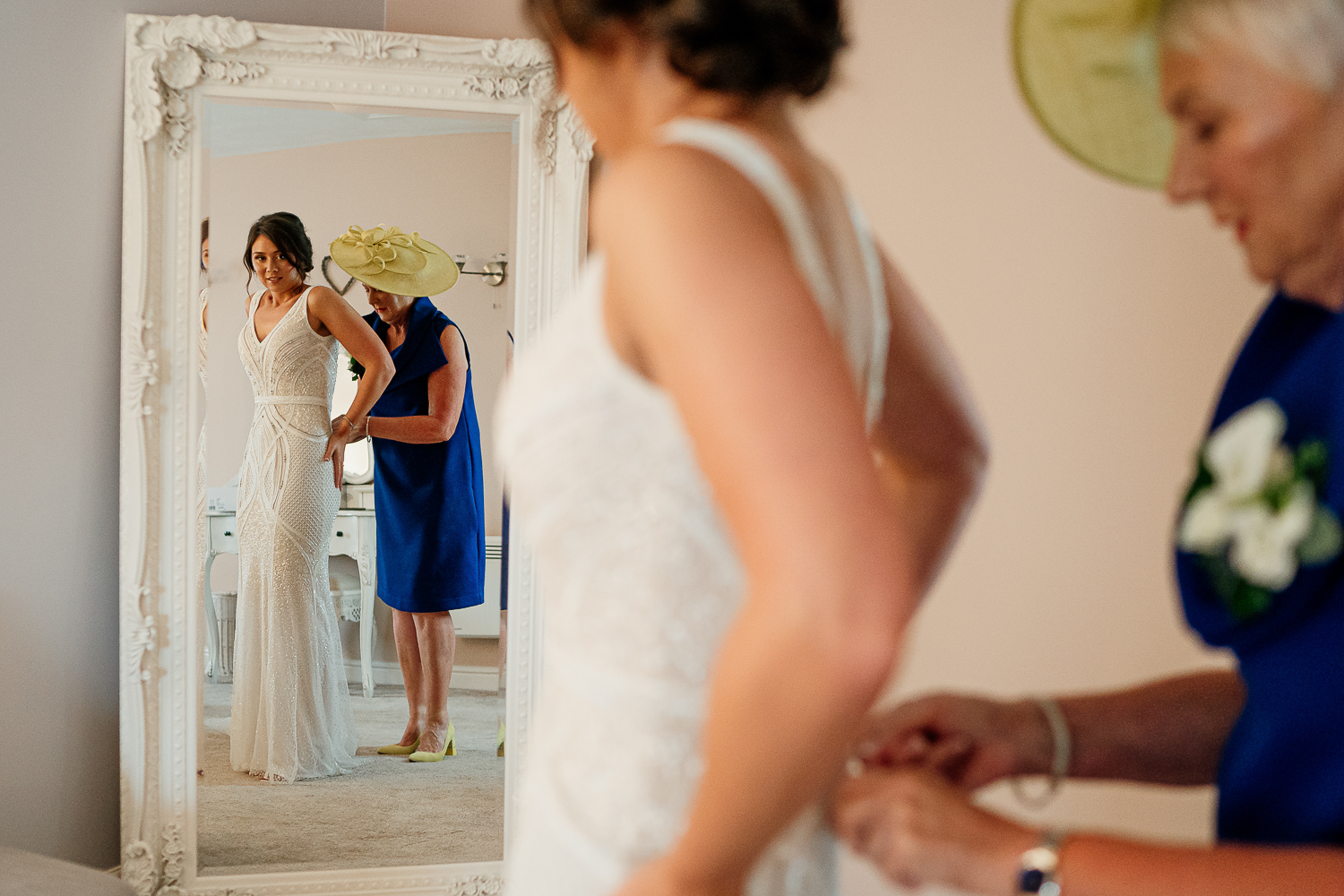 bride having her dress done up by mum