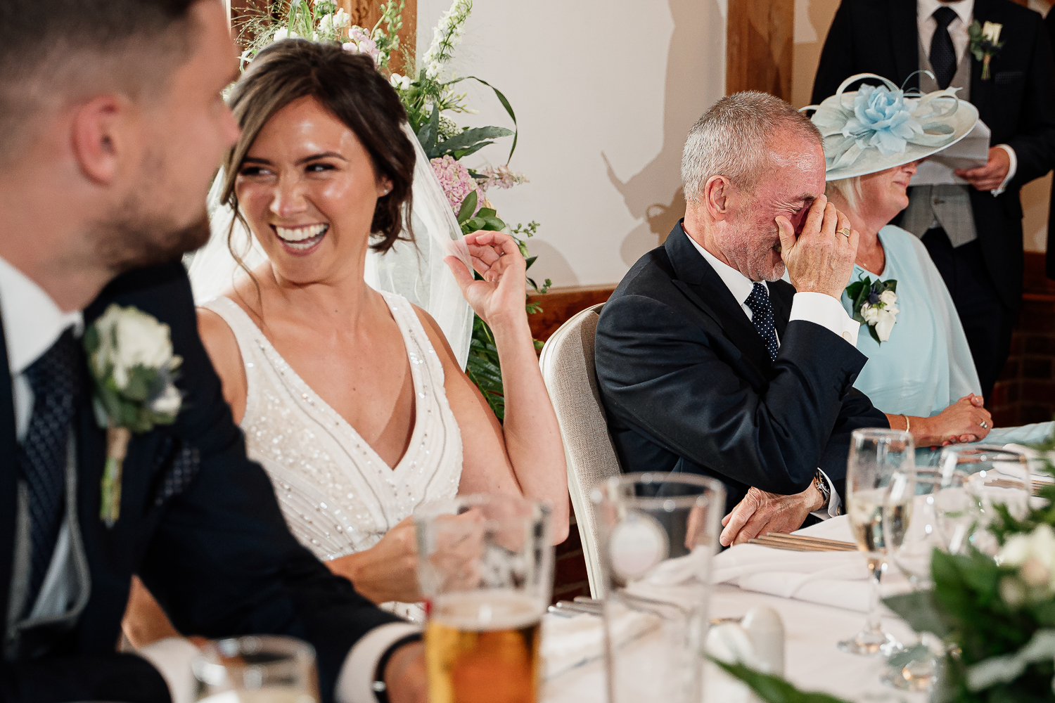 Bride laughing and her dad with head in hands