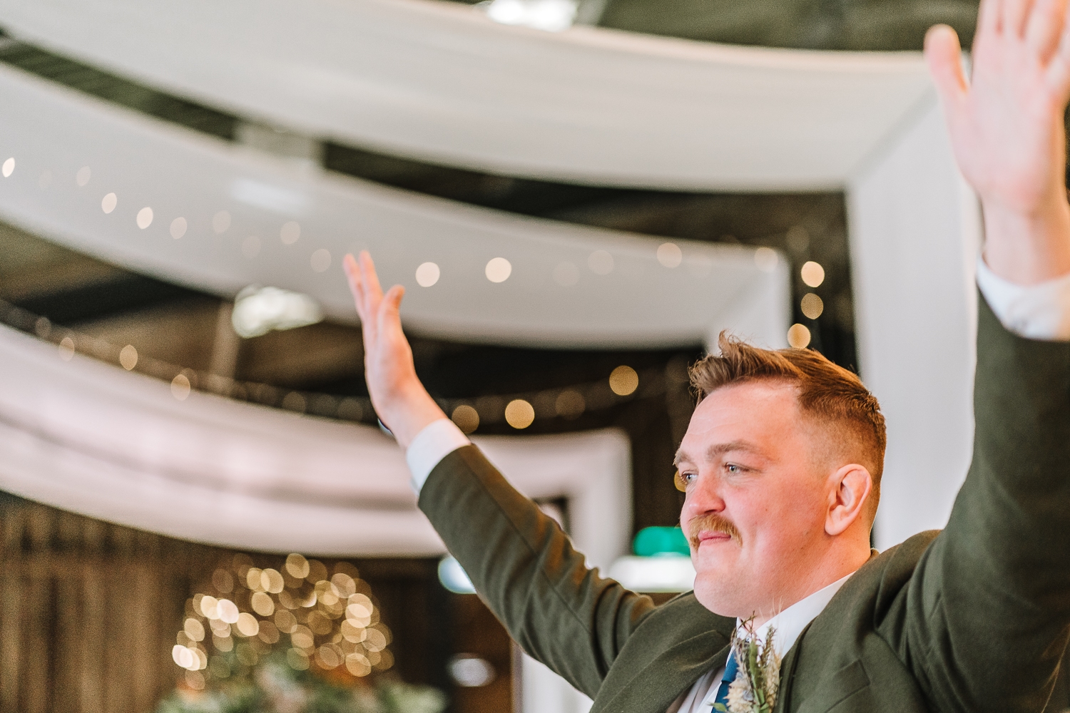 Groomsman laughing with hands up in the air